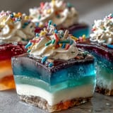 Festive rainbow Jello cups for kids feature fruity gelatin layers and a cloud of whipped topping—perfect for parties.
