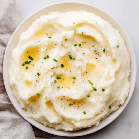 A close-up of creamy mashed potatoes, sprinkled with fresh herbs, an essential American side dish.