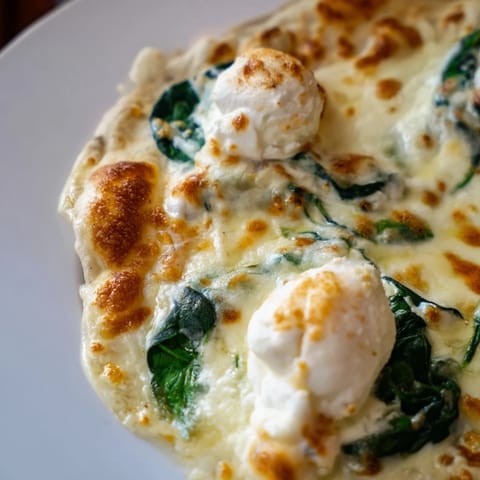 Overhead view of a homemade Spinach Ricotta Pizza with creamy ricotta dollops and garlic butter on a wooden board.  