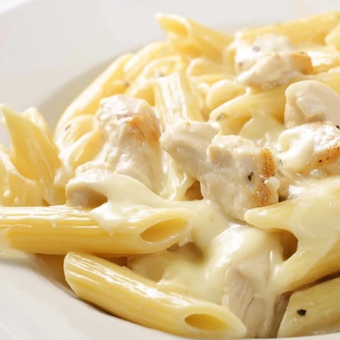 Creamy penne pasta with tender chicken and Alfredo sauce, served hot in a baking dish.