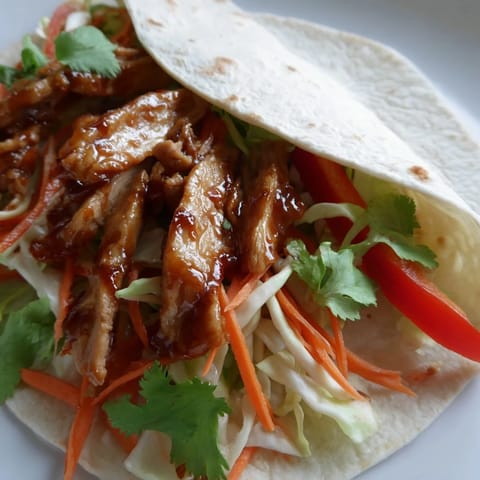 A close-up of glazed chicken strips and colorful veggies in a honey sriracha chicken wrap.  