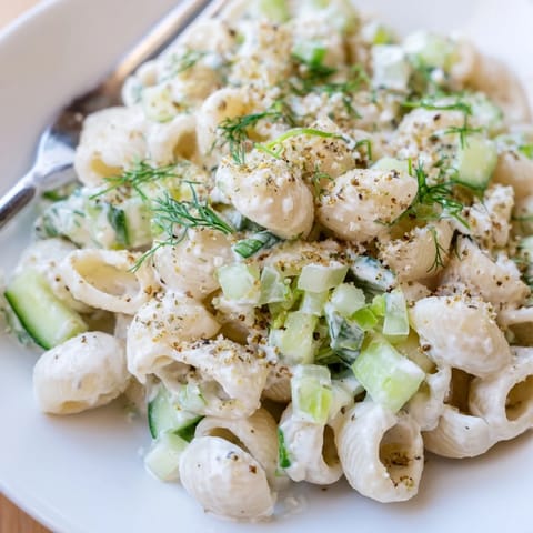 A chilled Cucumber Crunch Pasta Salad sits in a white bowl, ready for a summer picnic or BBQ.