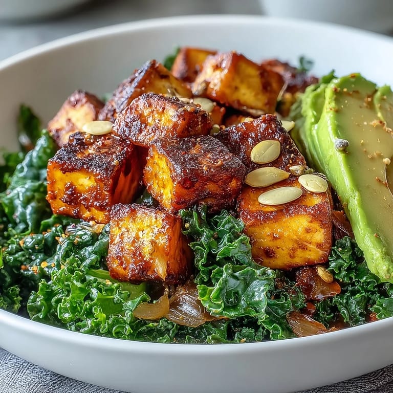 Crispy tofu, bright green kale, and sliced avocado topped with pumpkin seeds in a breakfast bowl.