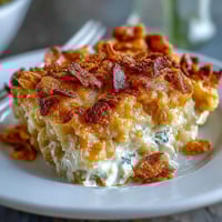 Lightened-Up Funeral Potatoes with Greek Yogurt Sauce in a golden casserole dish, topped with crispy cornflakes and melted cheese.